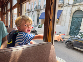 Happy little boy points outside the window during fun tram ride