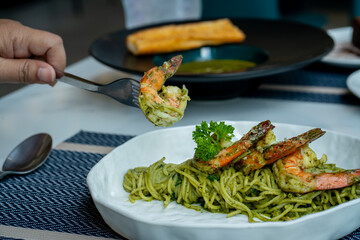People are scooping up shrimp spaghetti to eat.
