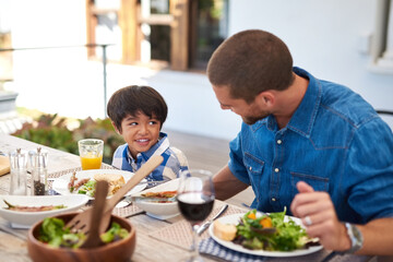 Dad, boy and happy with food in home at table on patio for lunch, bonding and thanksgiving. Parent, kid and smile for festive season or gathering for tradition, support and love with care and trust