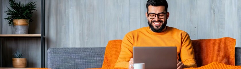 A smiling man works on a laptop, enjoying his cozy living space. Perfect for lifestyle, home office, and technology themes.