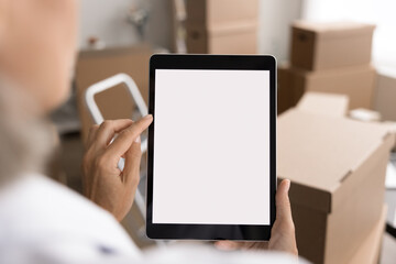 Small business owner, warehouse worker use tablet, manage inventory, process orders, coordinate logistics, communicate with client, device screen with white mock up view over female shoulder, close up