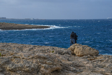 Ein Paar steht auf einem Felsen und schaut auf das Meer