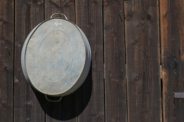 Wooden barn made of old darkened boards with a zinc tub. Texture of old boards as a background.