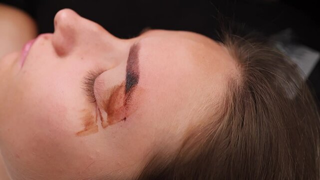 Close-up of the master's hands wiping off pigment residue from the eyebrows. Light permanent eyebrow makeup, performing eyebrow tattooing