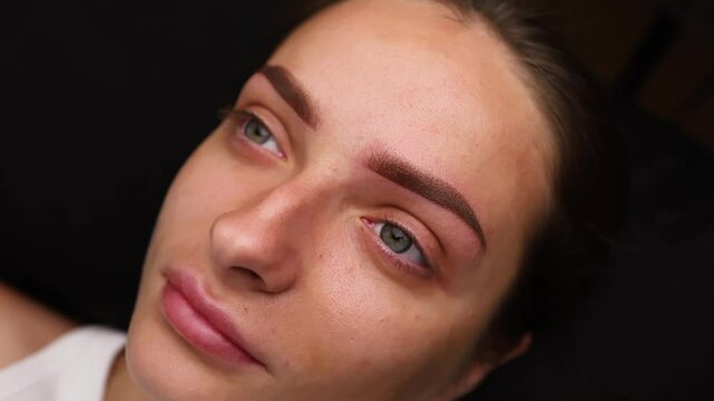 Performed work after permanent eyebrow makeup girl poses in front of the camera. Light permanent eyebrow makeup, performing eyebrow tattooing