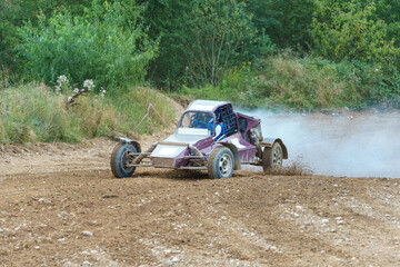 A close-up of an autocross racing car. Clouds of dust and sand burst out from under the wheels. Off-road racing.