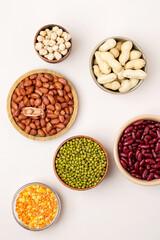 Assortment of legumes in bowls on a light background, top view.  Mung beans, chickpeas, peanuts, beans, lentils.