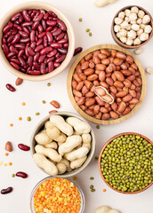 Assortment of legumes in bowls on a light background, top view. Mung beans, chickpeas, peanuts, beans, lentils.