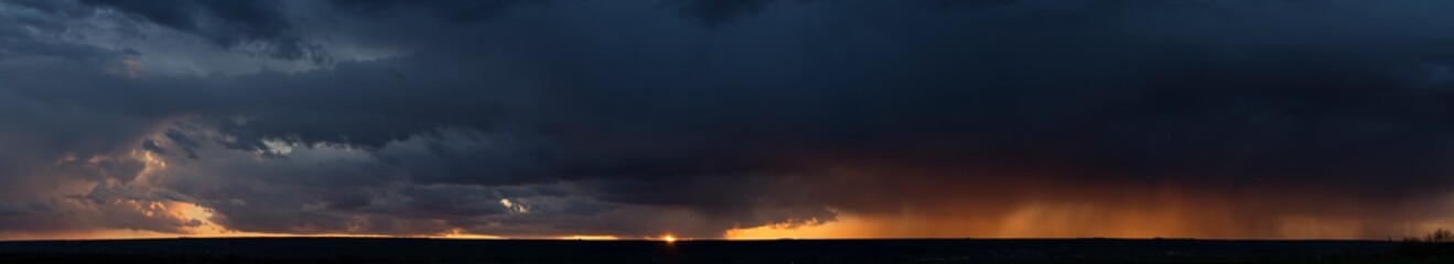 Landscape at sunset. A thunderstorm is approaching the village. Tragic gloomy sky. Panorama.