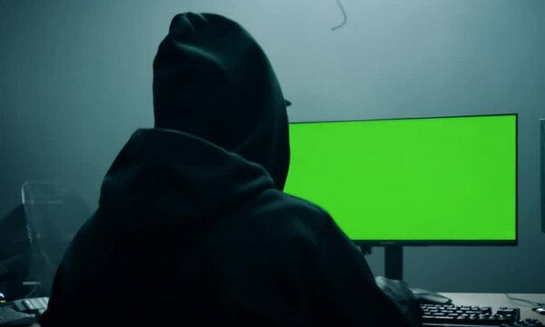 Over the shoulder hacker with green screen display