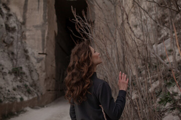 A beautiful woman dressed in gray pants and a sweater walks against the background of a career in stylish clothes