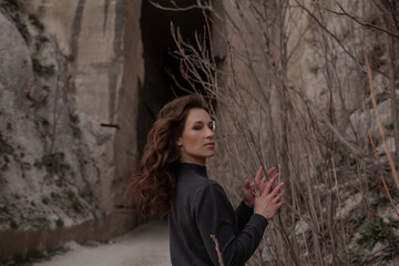 A beautiful woman dressed in gray pants and a sweater walks against the background of a career in stylish clothes