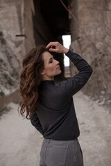 A beautiful woman dressed in gray pants and a sweater walks against the background of a career in stylish clothes