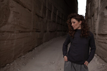 Obraz premium A beautiful woman dressed in gray pants and a sweater walks against the background of a career in stylish clothes