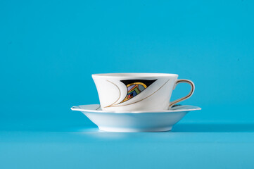 Empty cup and saucer on a blue background.