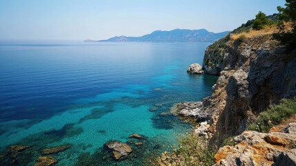 A serene sea view from a cliff, with clear water stretching out to the horizon and distant islands visible.