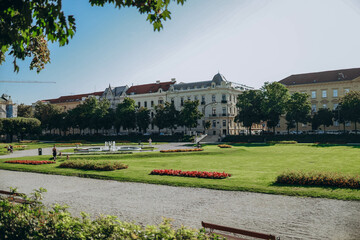 Obraz premium Croatian national leisurely strolls through a vibrant park in Zagreb, Croatia, surrounded by lush greenery, blooming flowers, and tall trees, enjoying the peaceful atmosphere and beautiful scenery