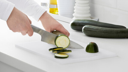 Closeup of a person slicing cucumbers on a plastic cutting board.