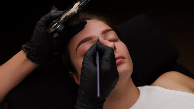 A young girl at the procedure has her eyelid tinted cream applied to her eyelid. Light permanent eyebrow makeup, performing eyebrow tattooing