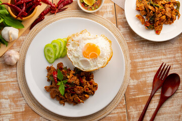 Stir fried sliced Beef with dry chilli and Holy Basil and cooked thai rice topped with fried egg in white plate.Thai famous food (pad kra pao prik hang).Top view.