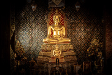 Thailand, August 11, 2024, Wat Phitchaya Yatikaram Worawihan, Golden Buddha statue within an ornate temple adorned with intricate patterns, surrounded by flowers and candles during evening hours
