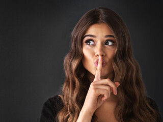 Naklejka premium Hair care, secret and woman with finger on lips for confidential hairstyle cosmetic or beauty. Privacy, silence or sign for quiet, whisper or shush hand gesture for gossip on black studio background