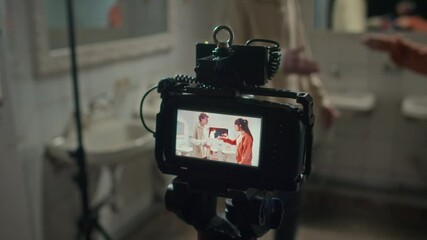 Over shoulder shot of camerawoman using professional video camera and recording couple arguing in public washroom - Powered by Adobe