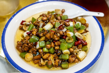 Serving of simple and authentic Sichuan cuisine of stir-fry diced celtuce with chicken meat, peanuts and scallion in oil