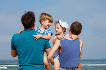 Fototapeta premium Parents, mom and dad carry their smiling children on ocean beach