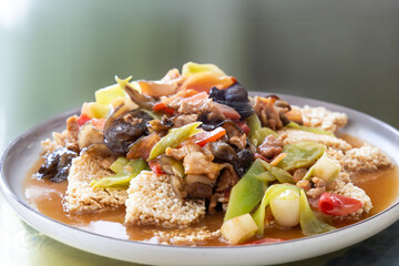 Serving of simple and authentic Sichuan cuisine of mixed stir fry of celtuce with pork slice, black fungus, chili pepper and rice cracker