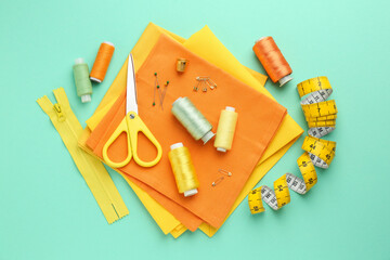 Flat lay composition with different sewing supplies on turquoise background