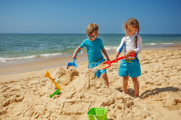 Kids have fun building sandcastles on the sunny beach vacations