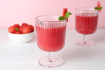 Tasty watermelon drink in glasses and fresh fruit on white wooden table, closeup