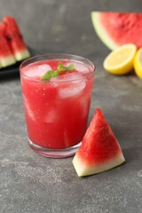 Tasty watermelon drink in glass, fresh fruits and mint on grey table