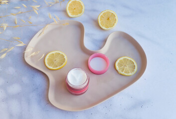 Vitamin C face cream with lemon slices on shadows background 