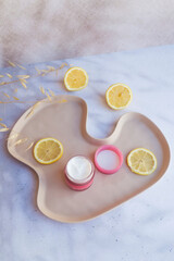 Vitamin C face cream with lemon slices on shadows background 