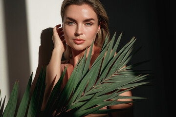 Young woman with blonde hair is holding a palm leaf  in sunlight © blackday