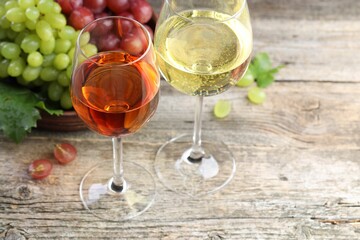 Fresh ripe grapes and glasses of wine on wooden table, closeup