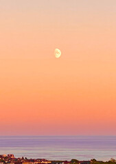 A full moon rises in a beautiful pastel coloured evening sky above the Irish Sea and the Isle of Man