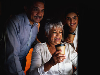 Group, night and reading in office, success and happy for sales of ebooks, deadline and computer for project. Dark, publisher and employees with smile for profit on app, coffee and mature woman