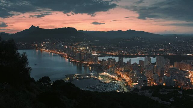 Timelapse video of Alicante city at sunset. Spanish coast at night with pink blue sky in the background. Night time timelapse of the coastline town and skyline. 