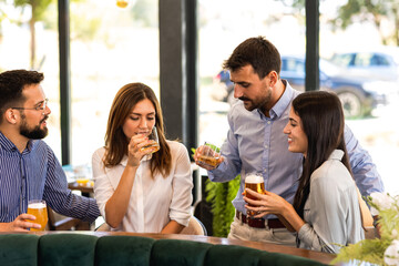 Group of friends hanging out in restaurant and drinking beer. Having fun, talking and making memories.