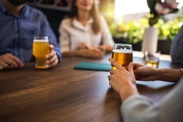Group of friends hanging out in restaurant and drinking beer. Having fun, talking and making memories.
