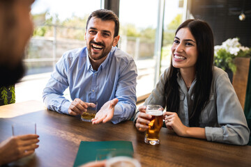 Group of friends hanging out in restaurant and drinking beer. Having fun, talking and making memories.