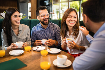 Group of friends hanging out at the restaurant. They laugh, talk and drink coffee.