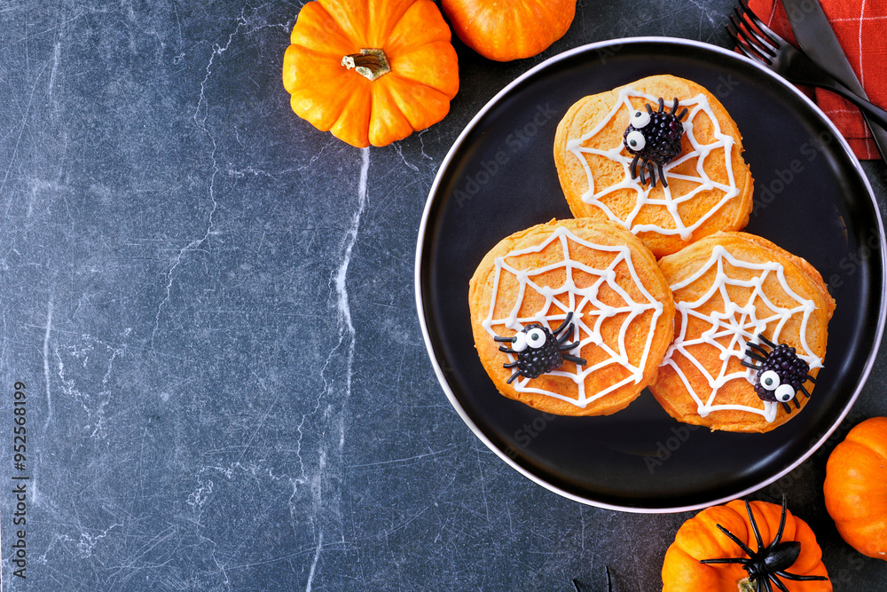 Poster fun halloween spider web pumpkin pancakes with blackberry spiders. top down view on a black plate ag