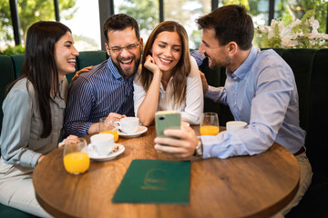 Group of friend met at the cafe. Looking at pictures on the phone. Having fun time together.