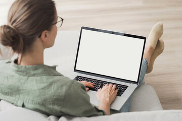 Young woman using laptop computer with blank empty white screen mockup at home. Freelance, student...