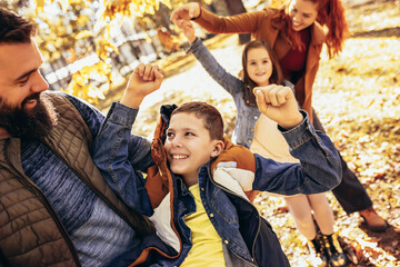 Parents tickle their children. Sunny autumn day in the colorful park