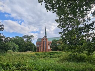 eine schöne Sicht auf Bäume, mit einem Wolkenhimmel und der Münsterkirche im Hintergrund: Bad Doberan, Mecklenburg - Vorpommern